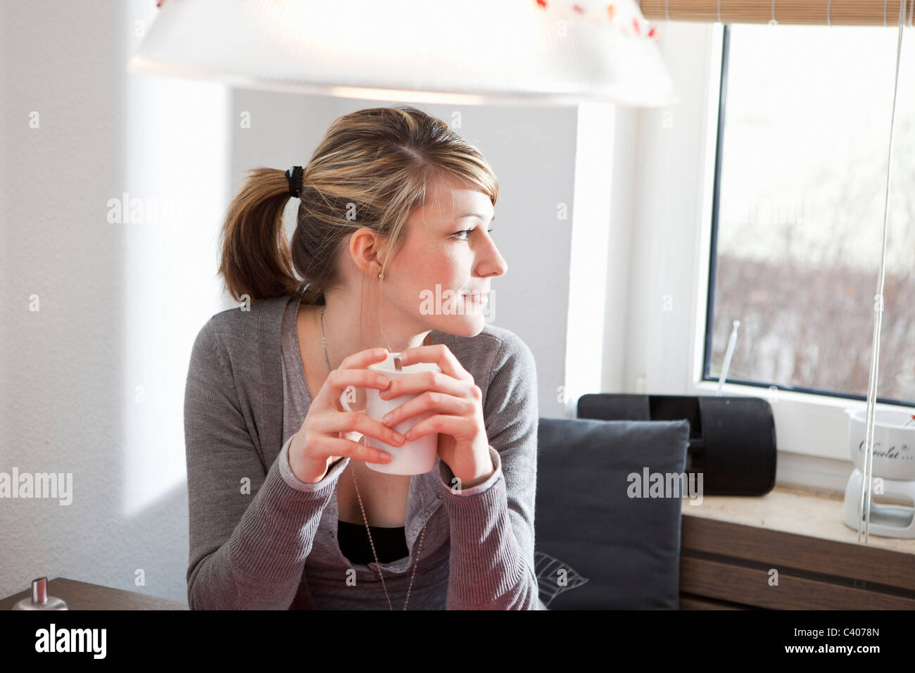 Woman in kitchen, looking out the window Stock Photo - Alamy