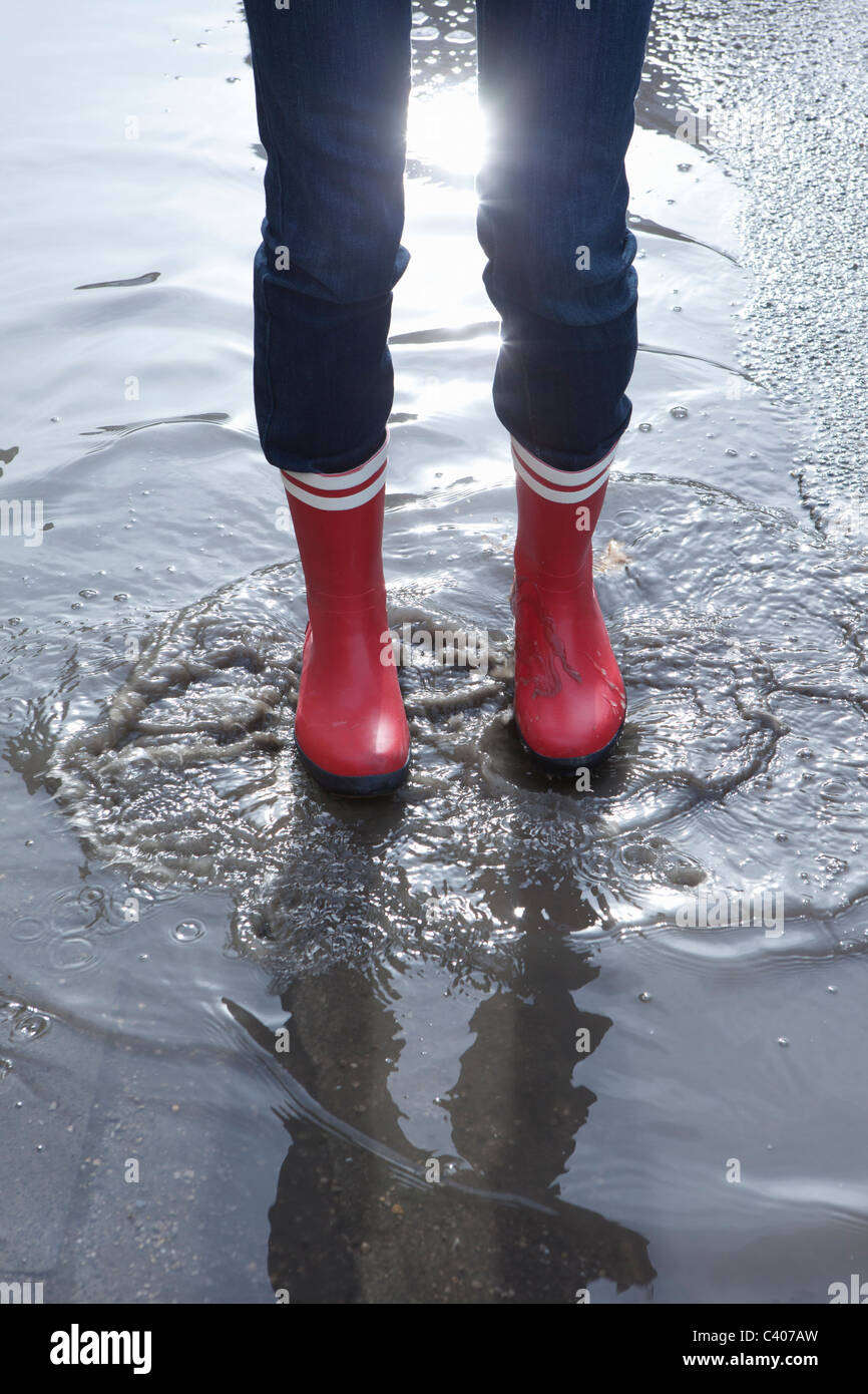 Close up rubber boots in puddle Stock Photo