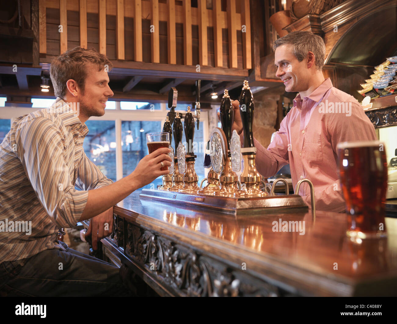 Landlord and customer in English pub Stock Photo
