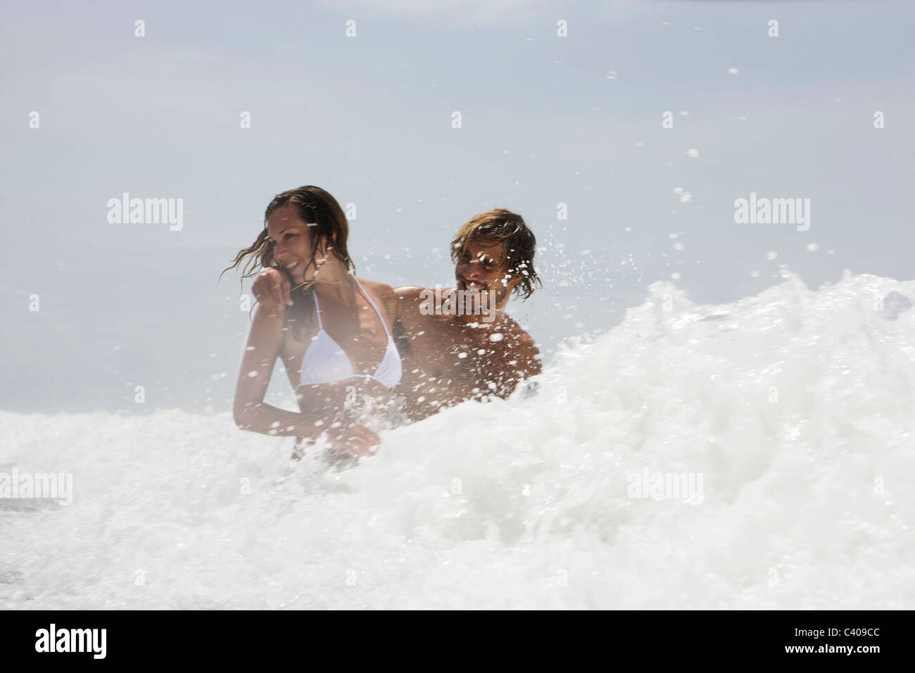 Guy and girl in wave, laughing Stock Photo