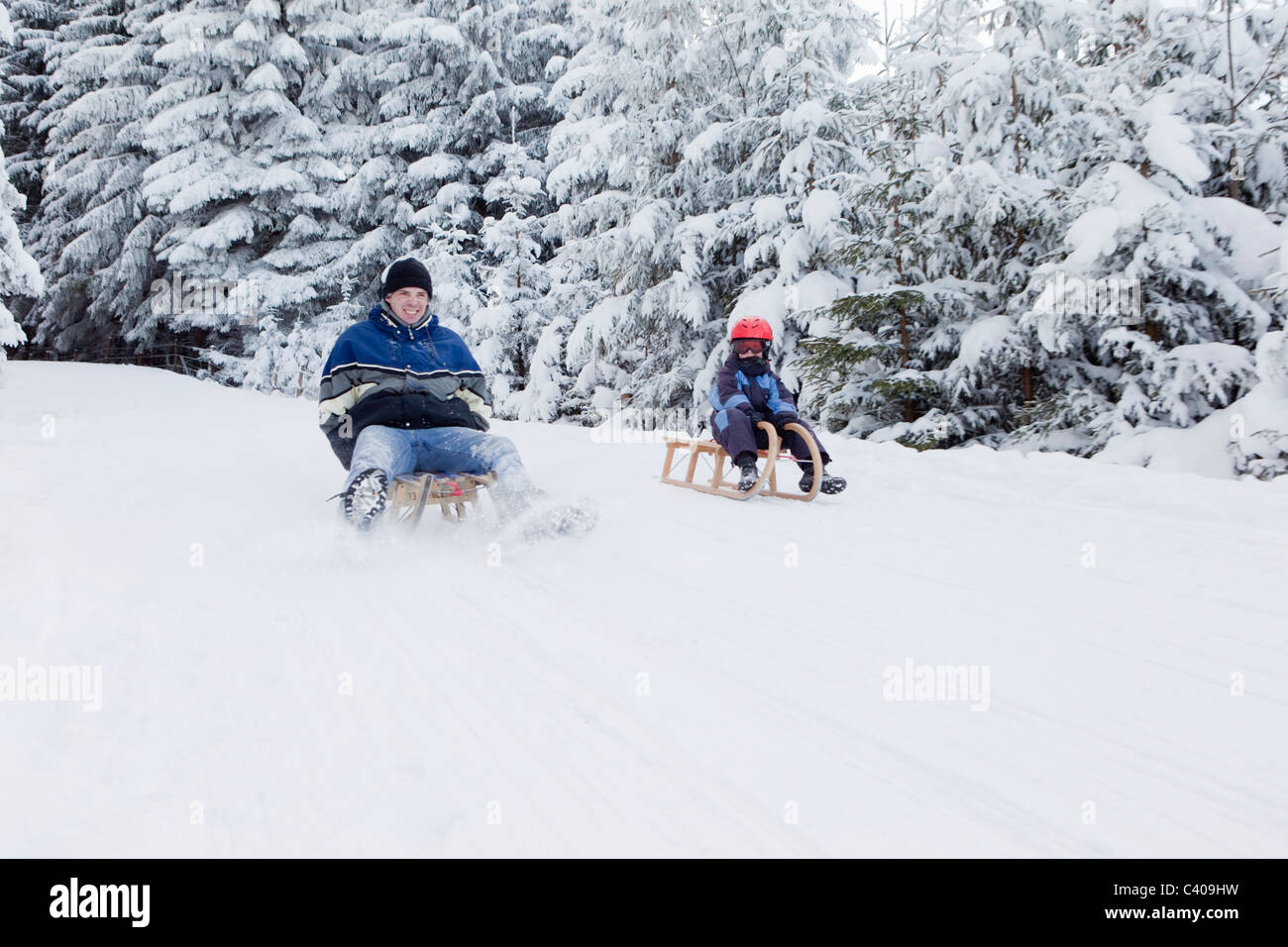 Man and boy sledding downhill Stock Photo