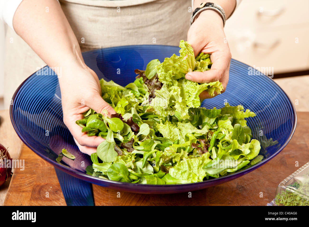 Chef mixing a salad of various sorts of lettuce in a blue bowl Stock Photo