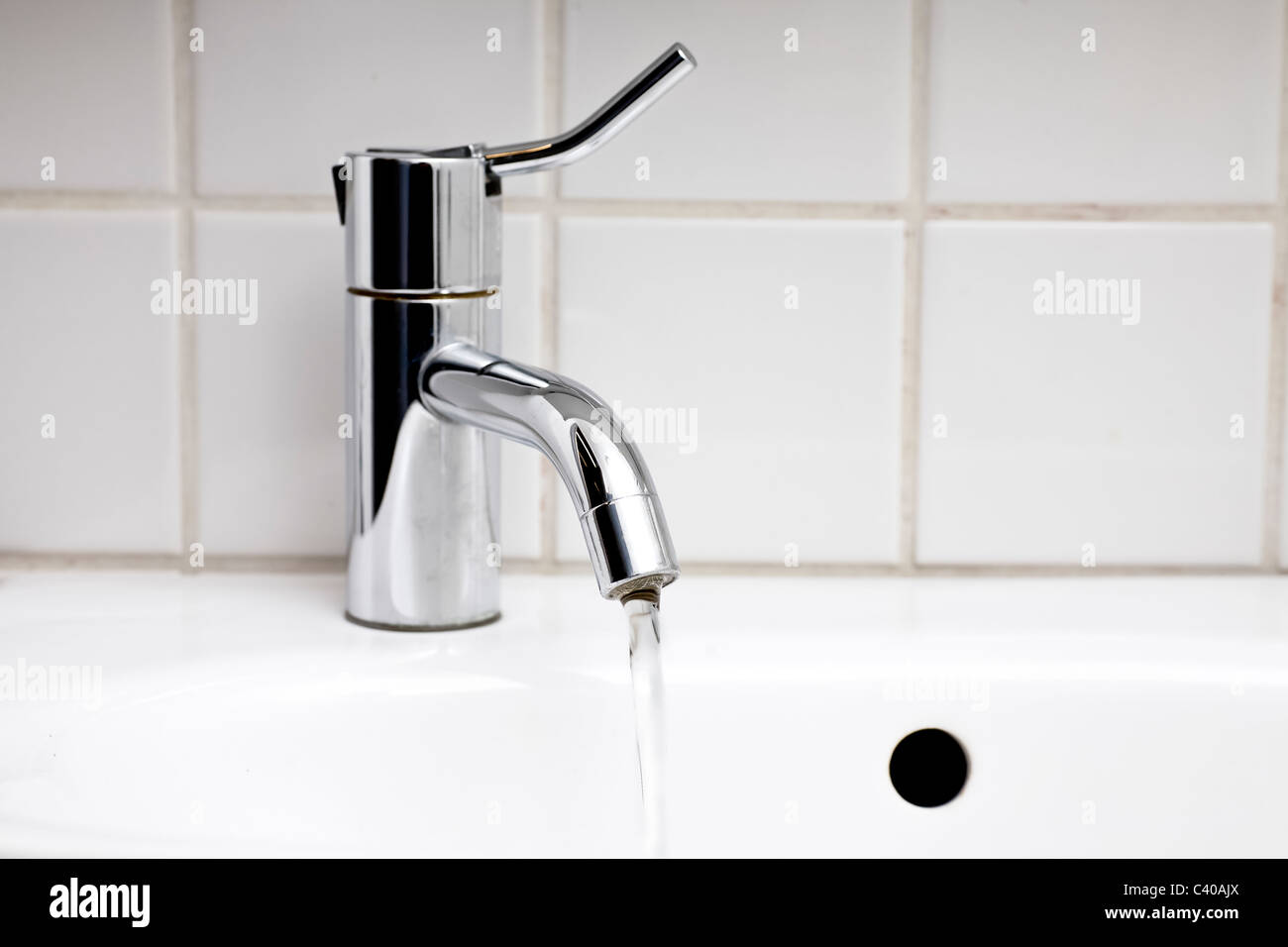 close up of sink and tap with running water in bathroom Stock Photo