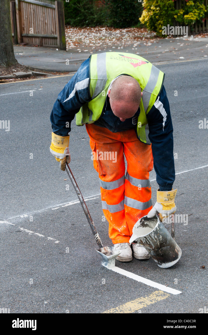 Workers from Alexander Highways UK marking yellow lines and parking bays. Stock Photo