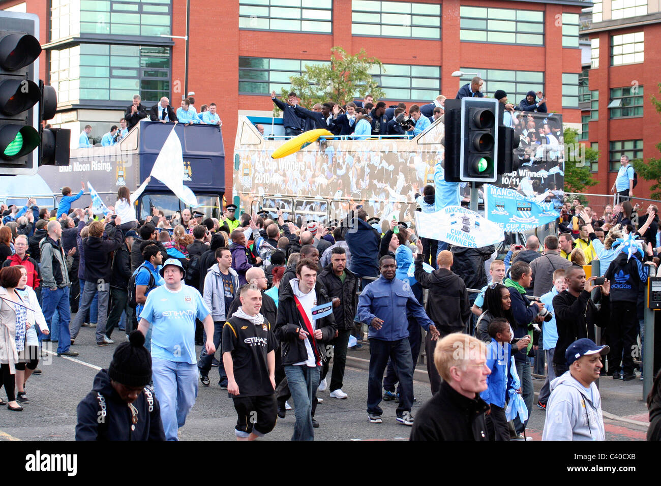 Fans walk alongside the tour bus, Manchester City Cup Parade, 2011 Stock Photo
