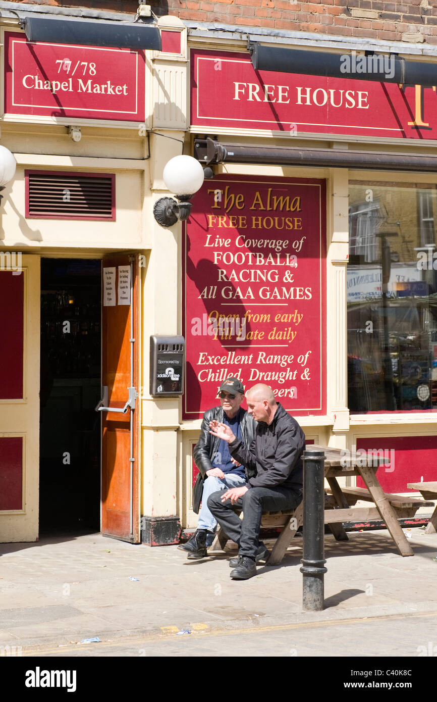 London , Islington , Chapel Market , The Alma free house traditional local pub or bar with two men smoking seated outside Stock Photo