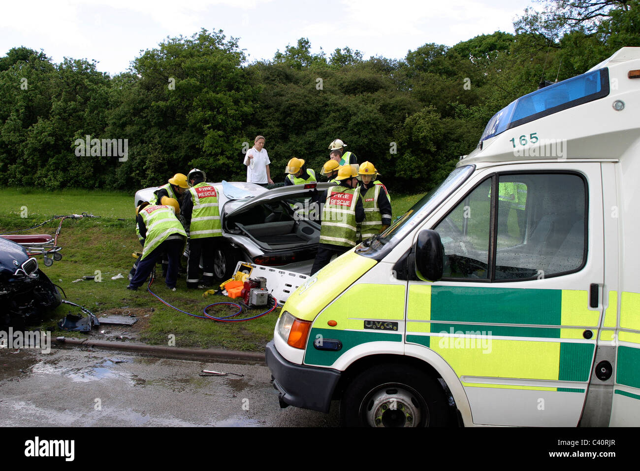 Firemen cut a casualty out of his car following an accident Stock Photo