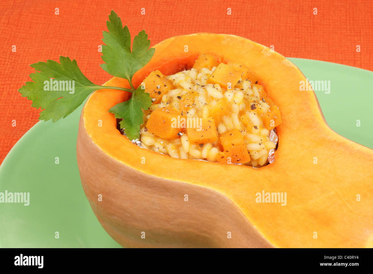 Half pumpkin filled with pumpkin risotto served on a green plate Stock Photo