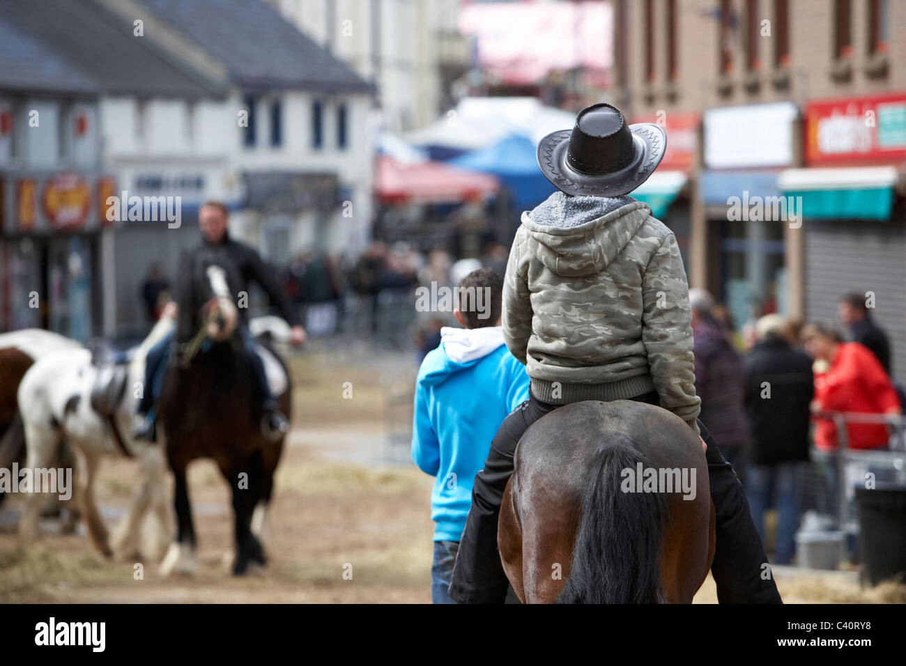 man in cowboy hat riding horse down main street during ballyclare may
