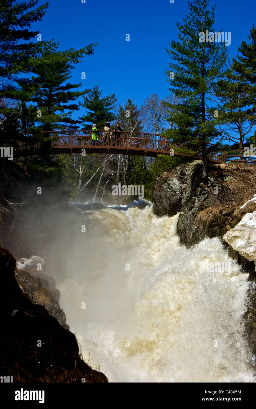 Group standing on bridge over seven raging waterfalls Maskinongé river