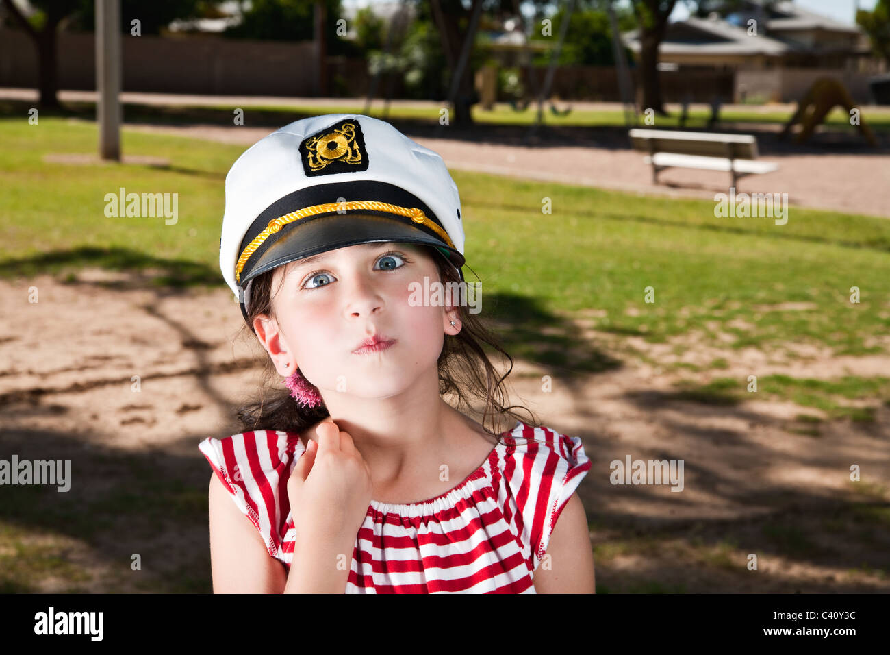 a young girl wearing a captains hat and making a funny expression Stock