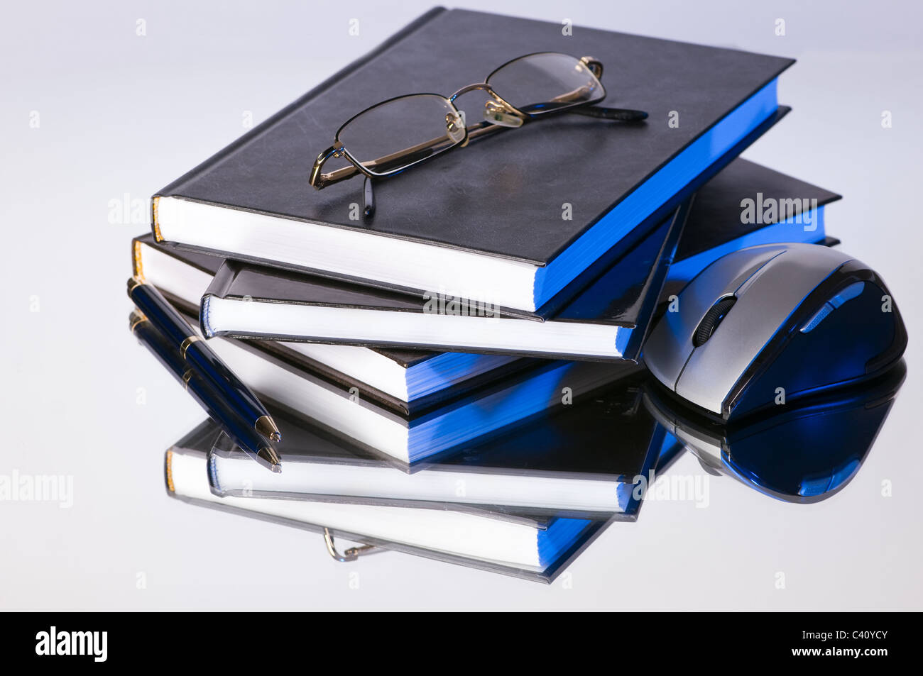 stack of books with pen glasses and a computer mouse Stock Photo