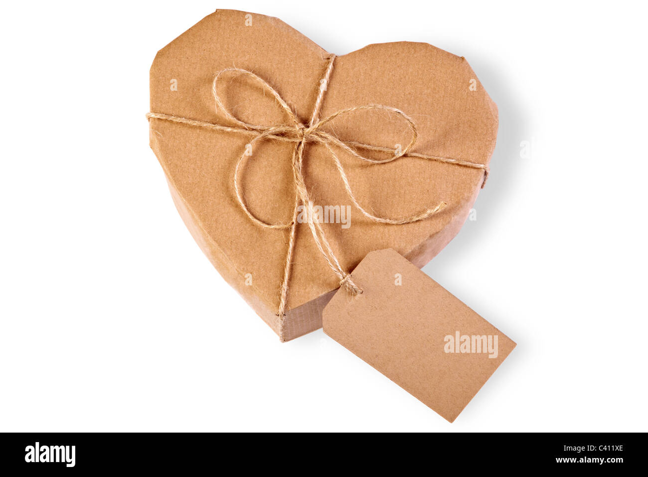 Photo of a heart gift box wrapped in brown paper with label, isolated on a white background. Stock Photo