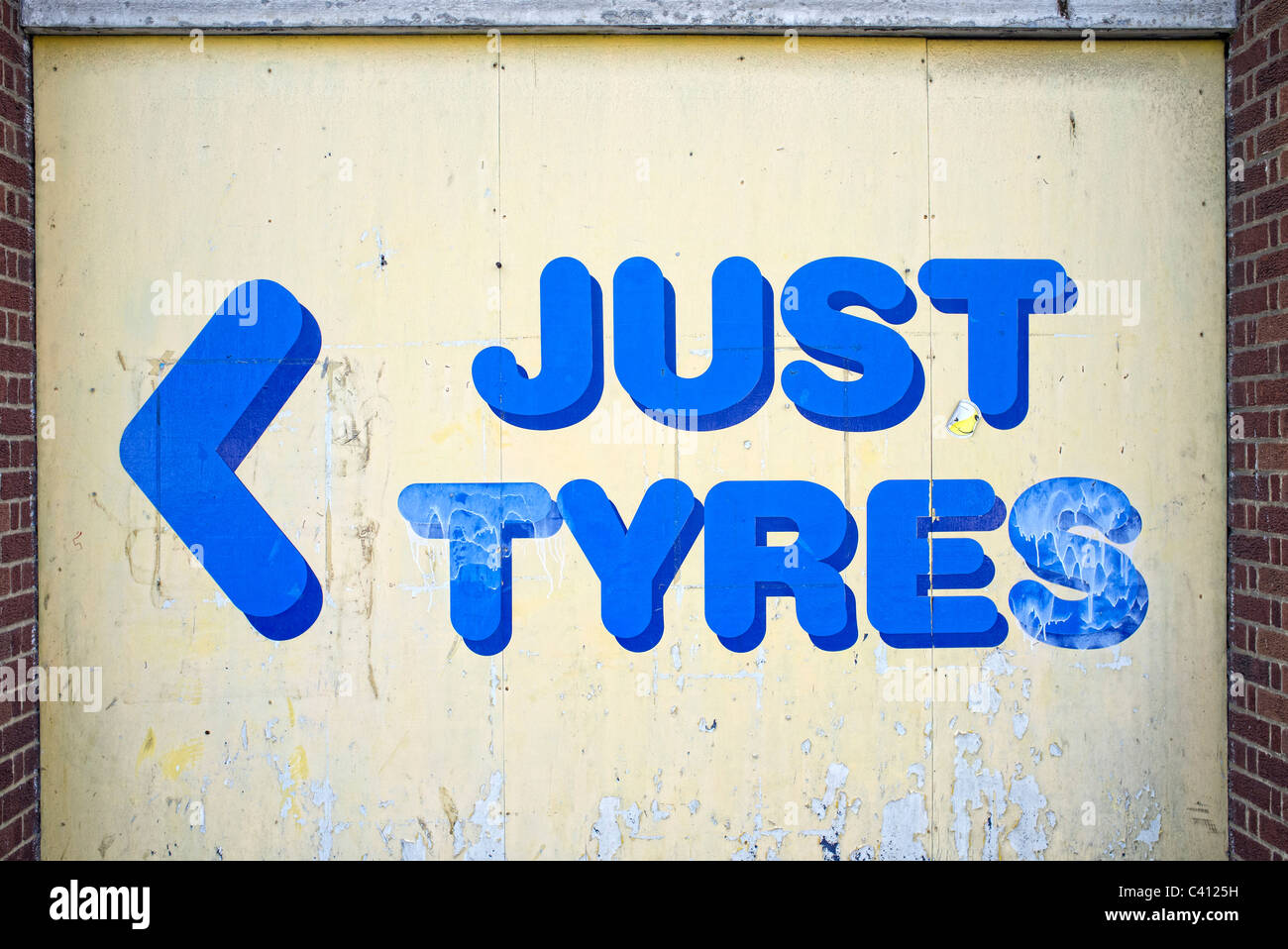 peeling blue and yellow sign just tyres Stock Photo