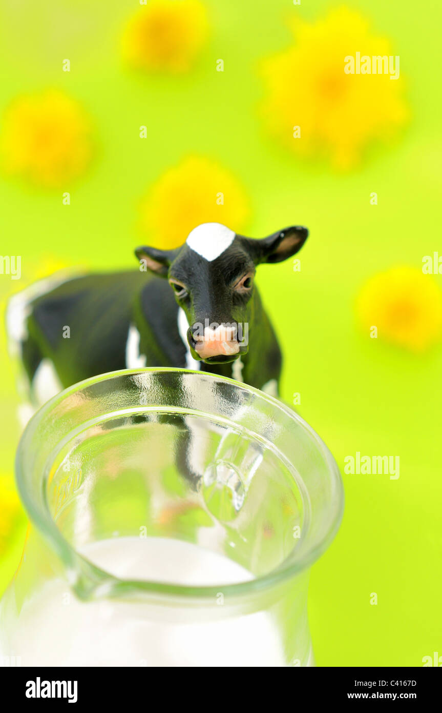 A cow and a milk jug against a bright green background Stock Photo