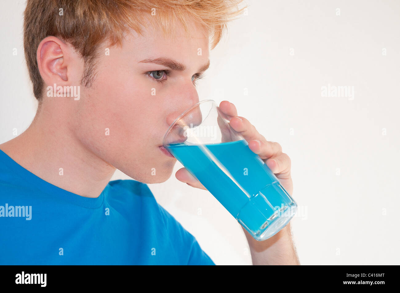 Young man drinking blue soft drink. Close view. Stock Photo