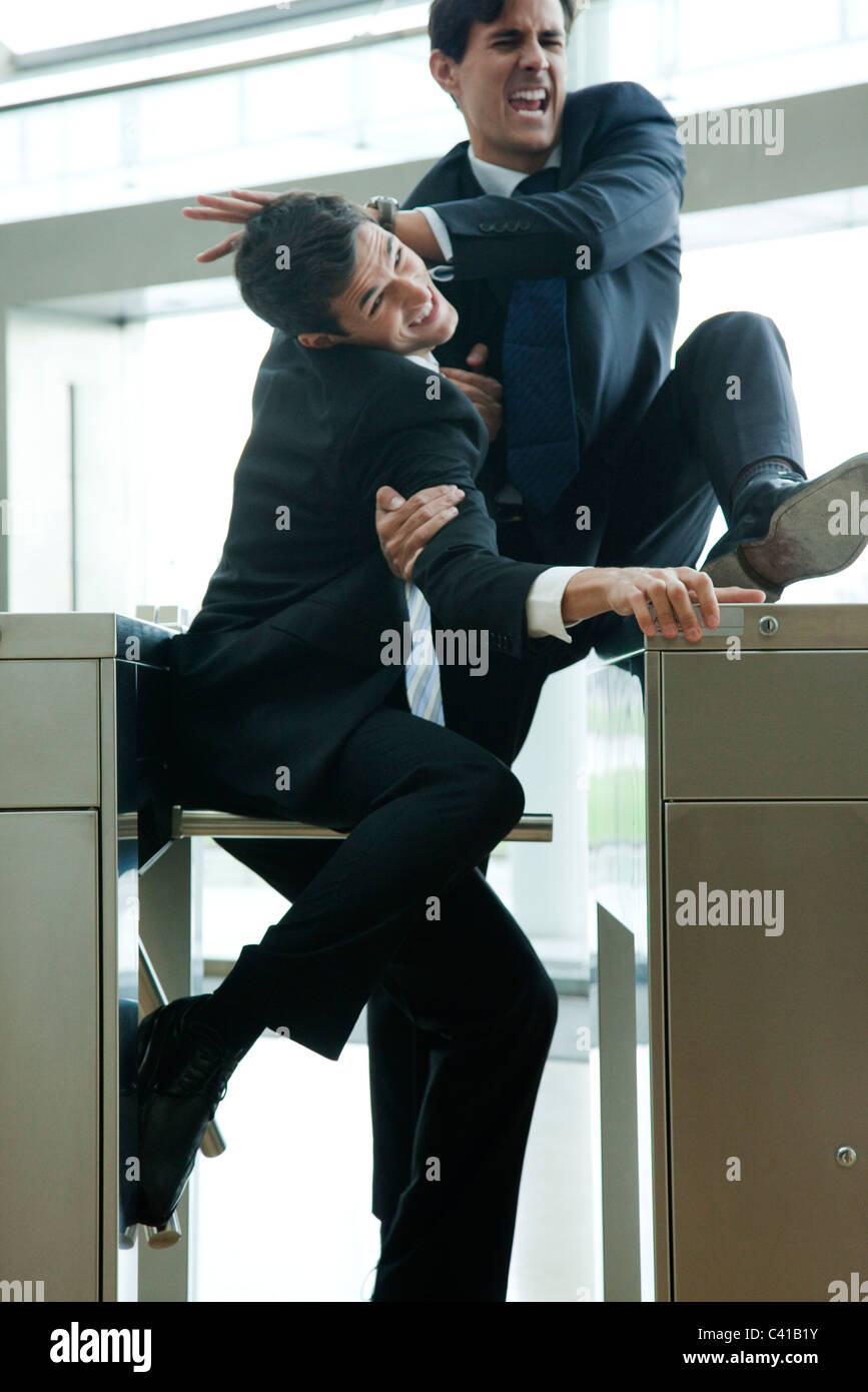 Businessmen fighting to beat each other through turnstile Stock Photo
