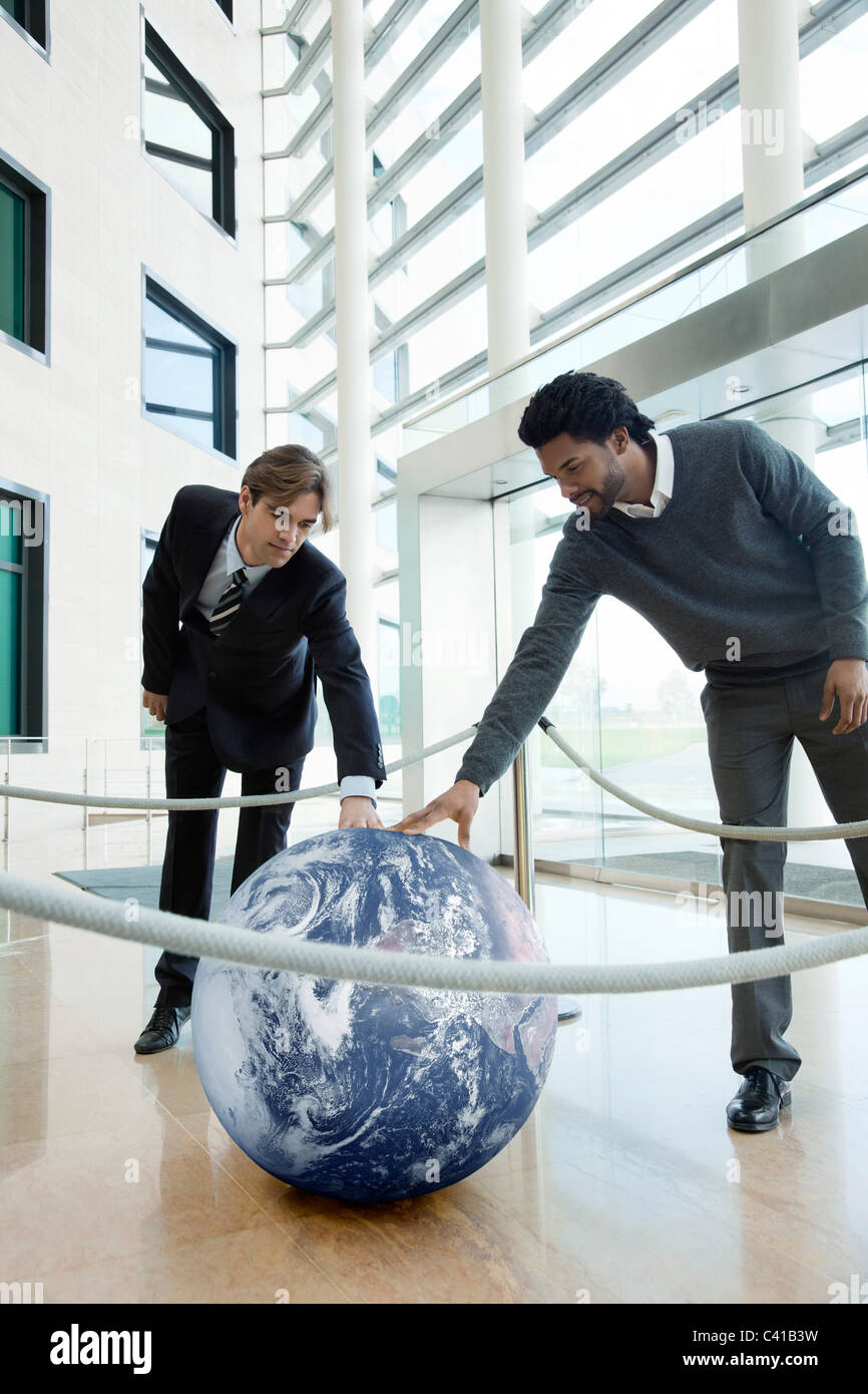 Businessmen touching ball contained in roped off area Stock Photo Alamy