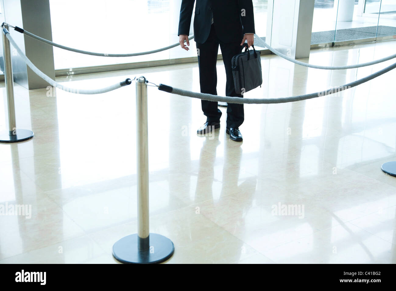 Businessman standing inside roped off area in lobby Stock Photo Alamy