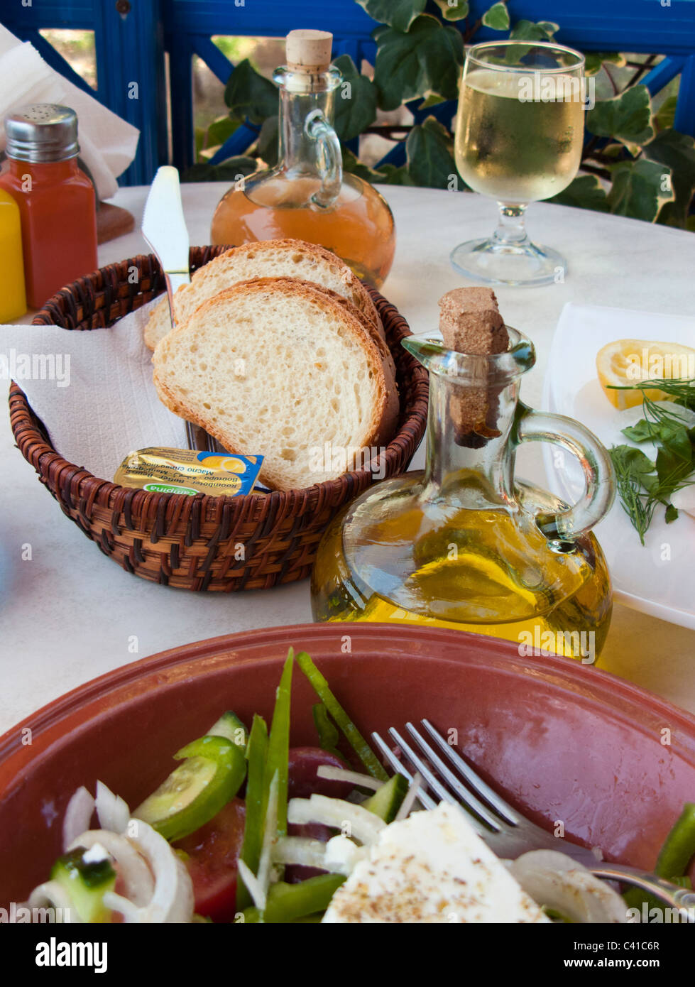 SELECTIVE FOCUS IMAGE OF OLIVE OIL AND BREAD IN A GREEK TAVERNA WITH SALAD IN THE FOREGROUND Stock Photo