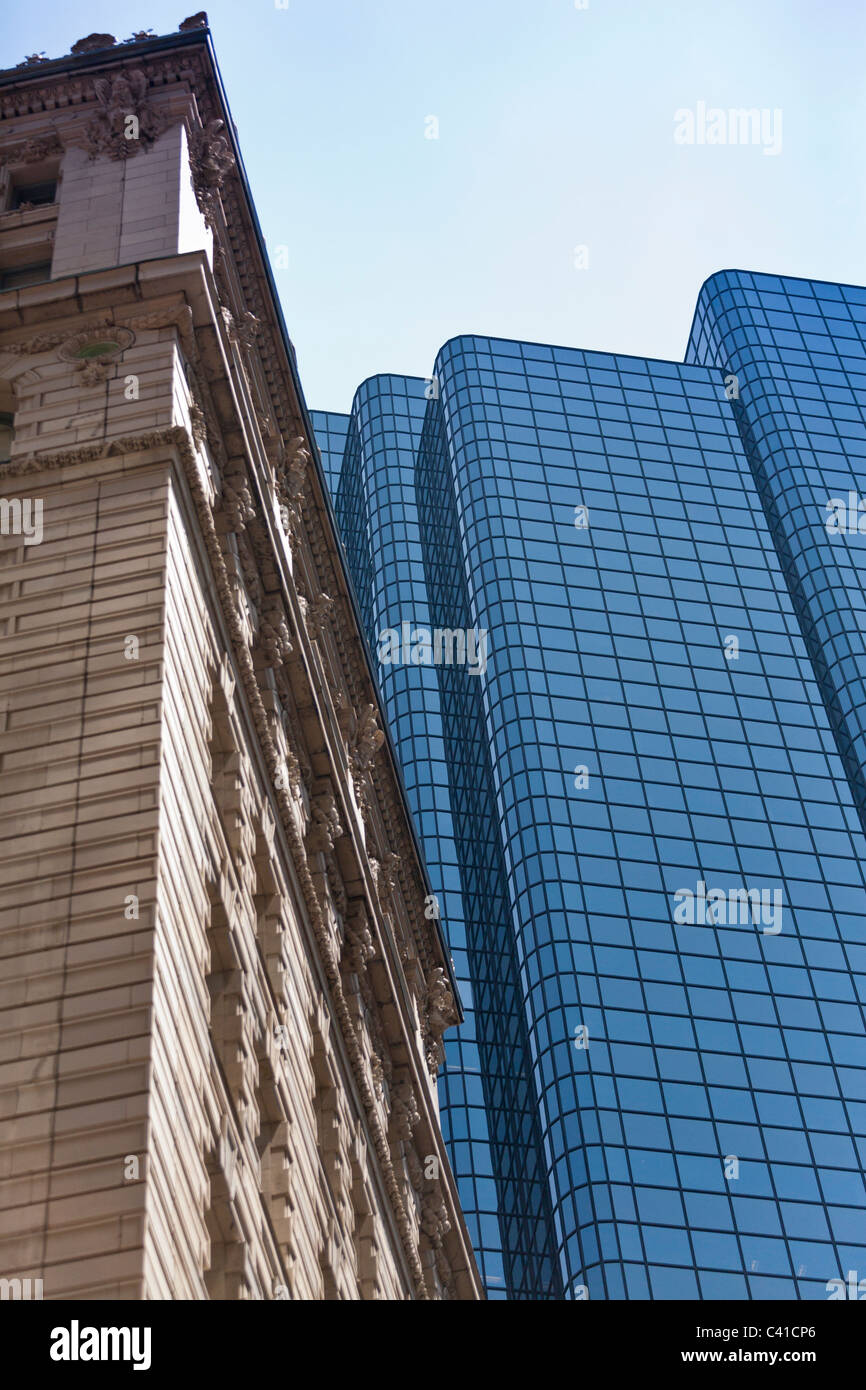 Architecture, old and new. An old ornately carved stone faced building with an anonymous blue glass glazed office tower Stock Photo