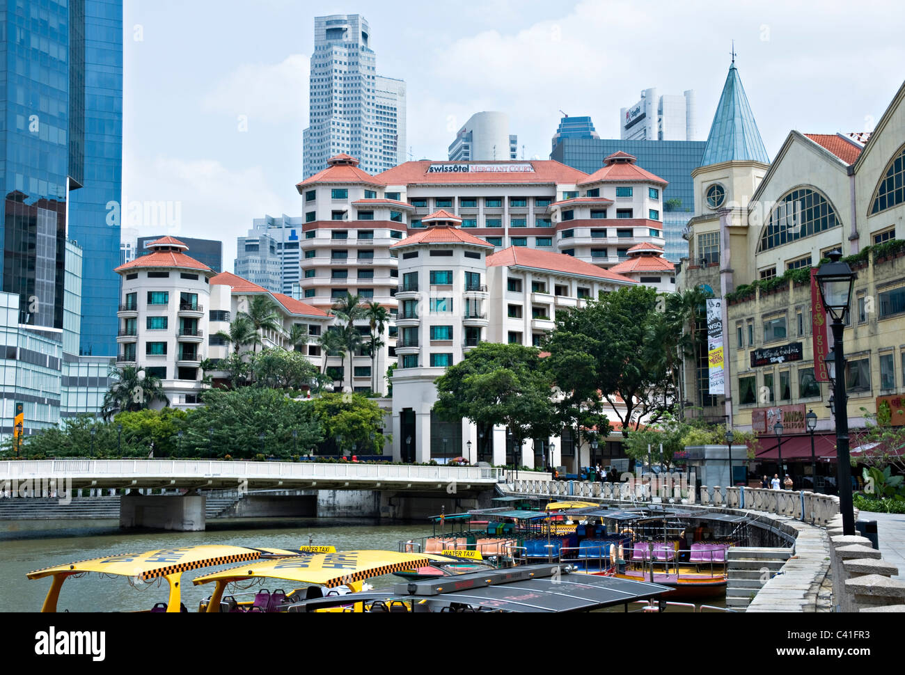 Swissotel Merchant Court with The City Skyscrapers Behind and Boats on Singapore River near Clarke Quay Republic of Singapore Stock Photo