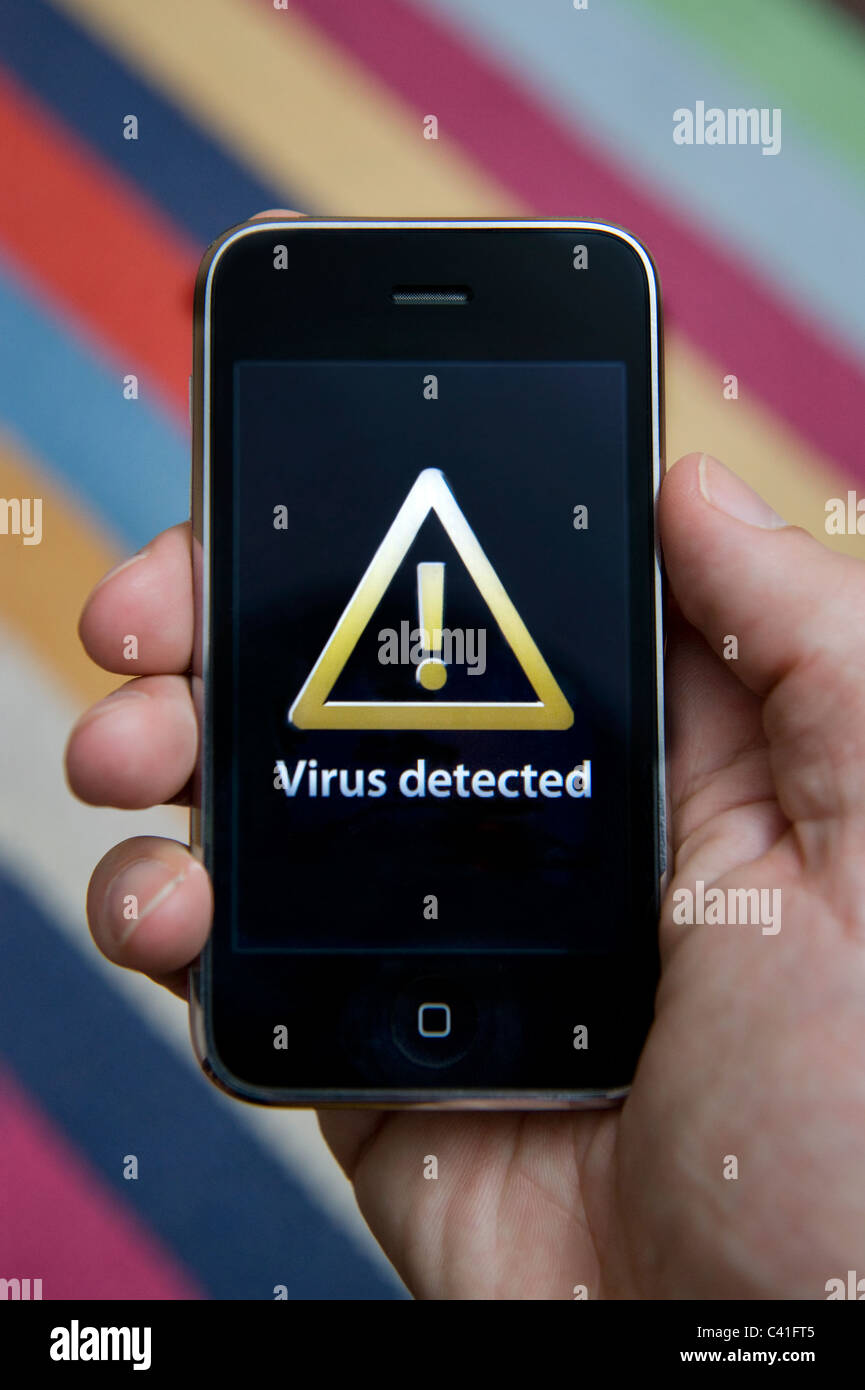 Close up of male hand holding an iPhone which is indicating the detection of a virus. (Editorial use only). Stock Photo