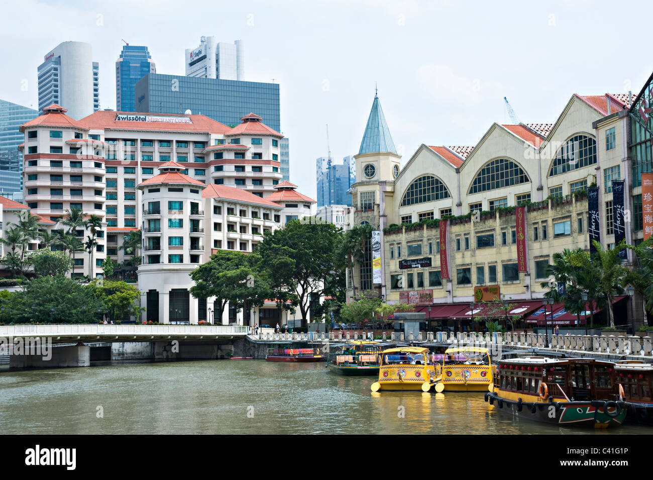 Swissotel Merchant Court with The City Skyscrapers Behind and Boats on Singapore River near Clarke Quay Republic of Singapore Stock Photo