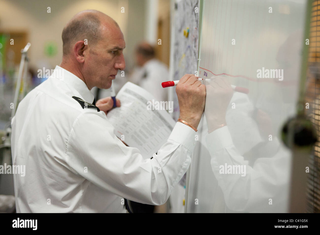 A police sergeant writes details on a wipe board in the Metropolitan Police's Special Operations Centre, in Lambeth (London). Stock Photo