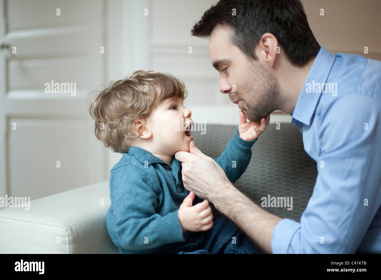 Father examining toddler son's teeth, portrait Stock Photo