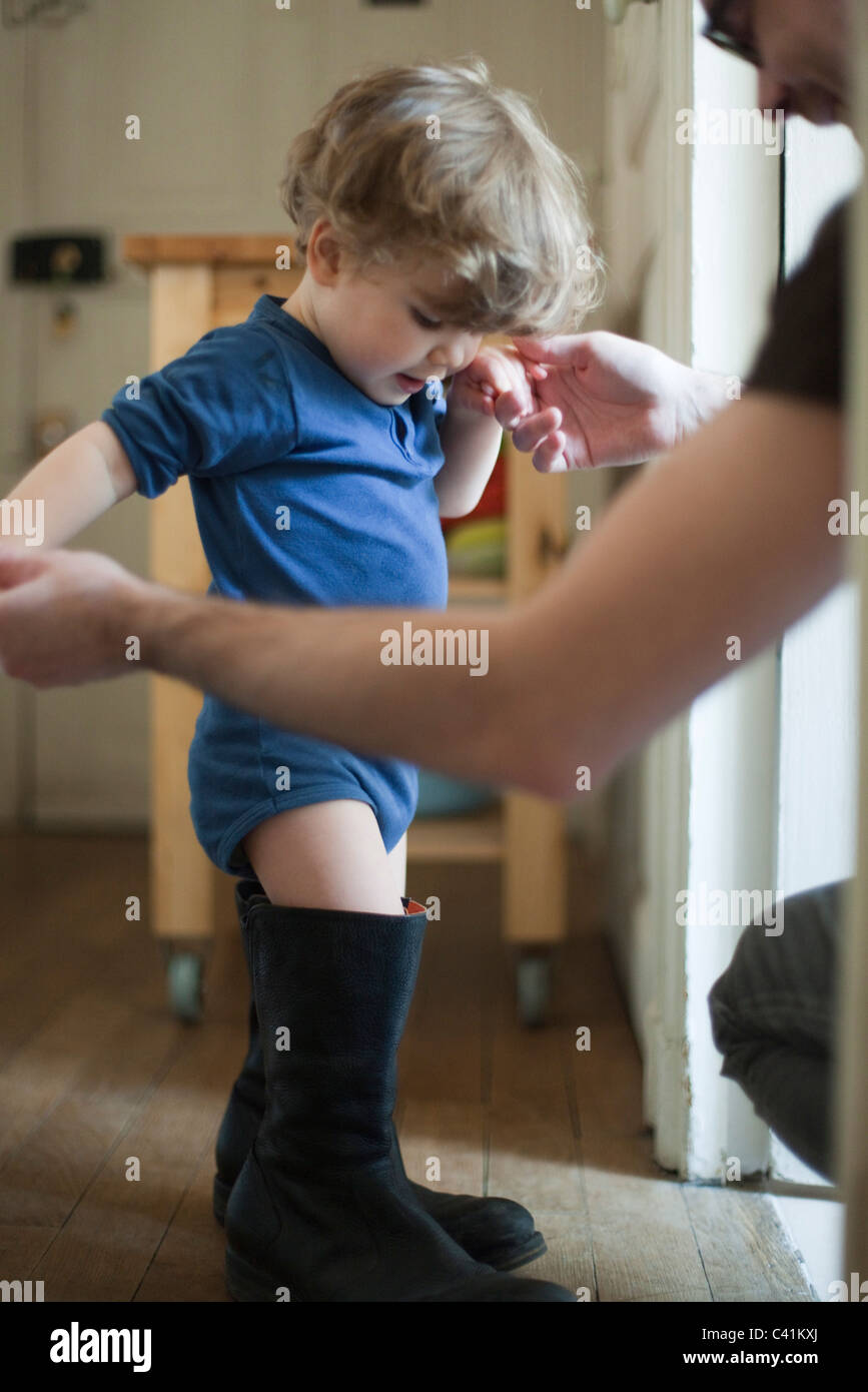 Toddler boy learning to walk in father's boots Stock Photo