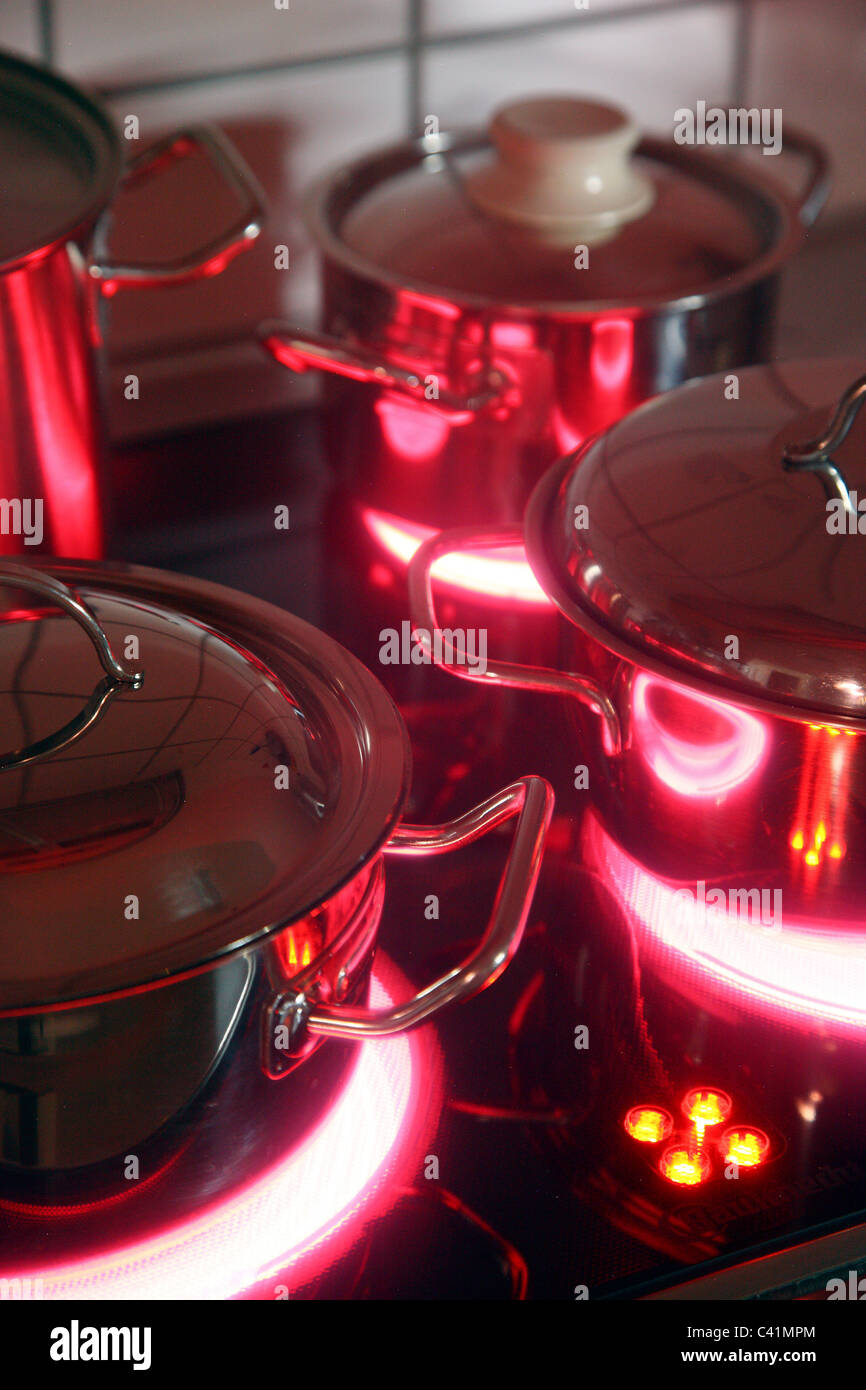 home kitchen, cooking pots, made of stainless steel, on a hot glass-ceramic cooking ring. red, hot glowing. Stock Photo