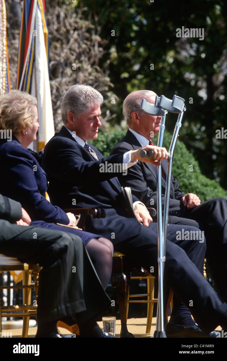 President Bill Clinton with crutches seated with Madeleine Albright and James Baker at the White
