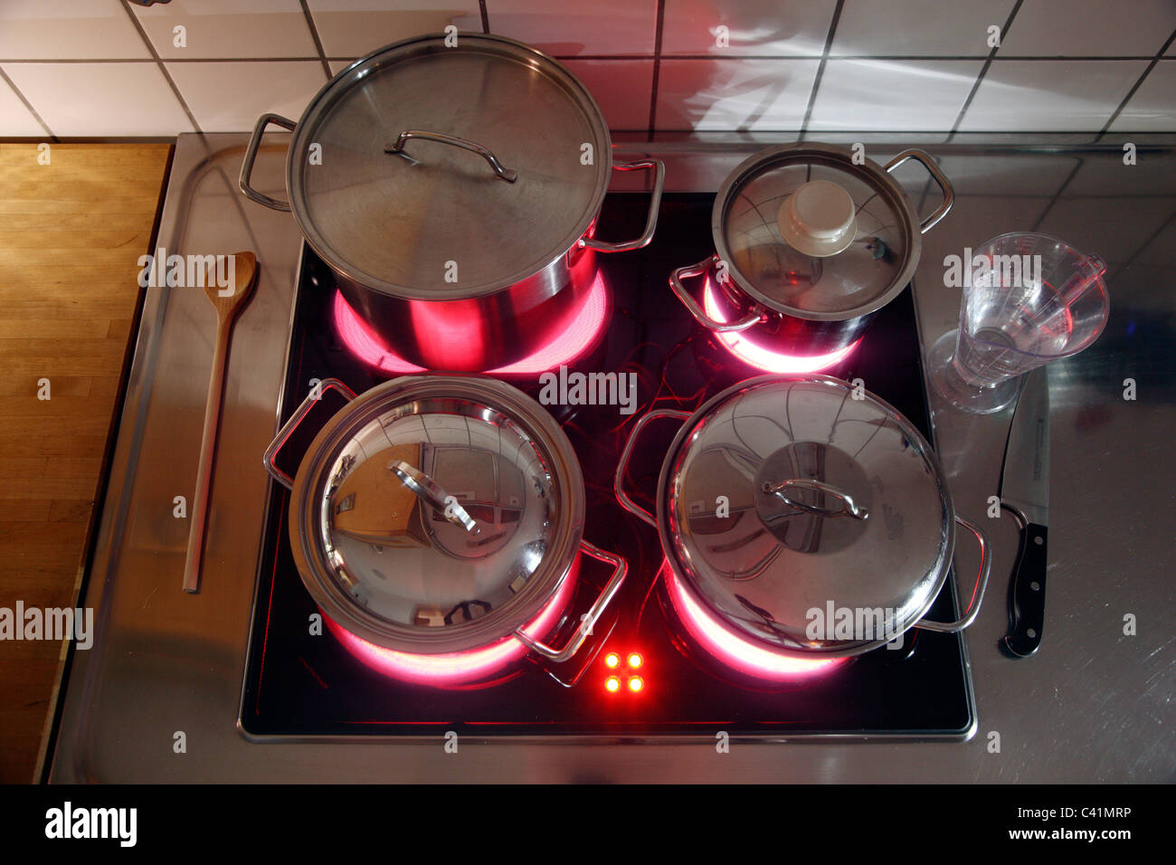 home kitchen, cooking pots, made of stainless steel, on a hot glass-ceramic cooking ring. red, hot glowing. Stock Photo