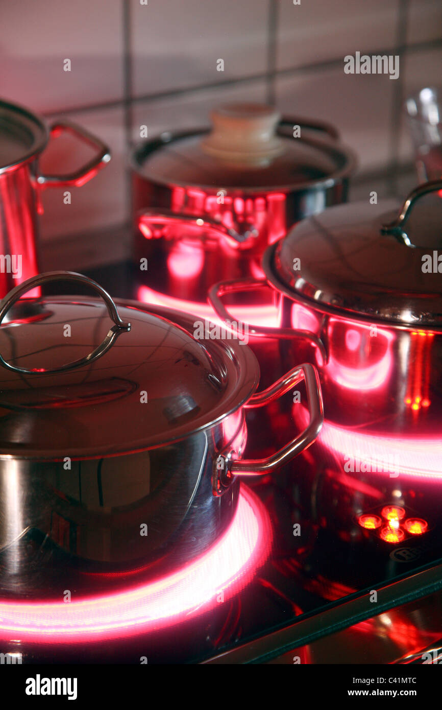 home kitchen, cooking pots, made of stainless steel, on a hot glass-ceramic cooking ring. red, hot glowing. Stock Photo