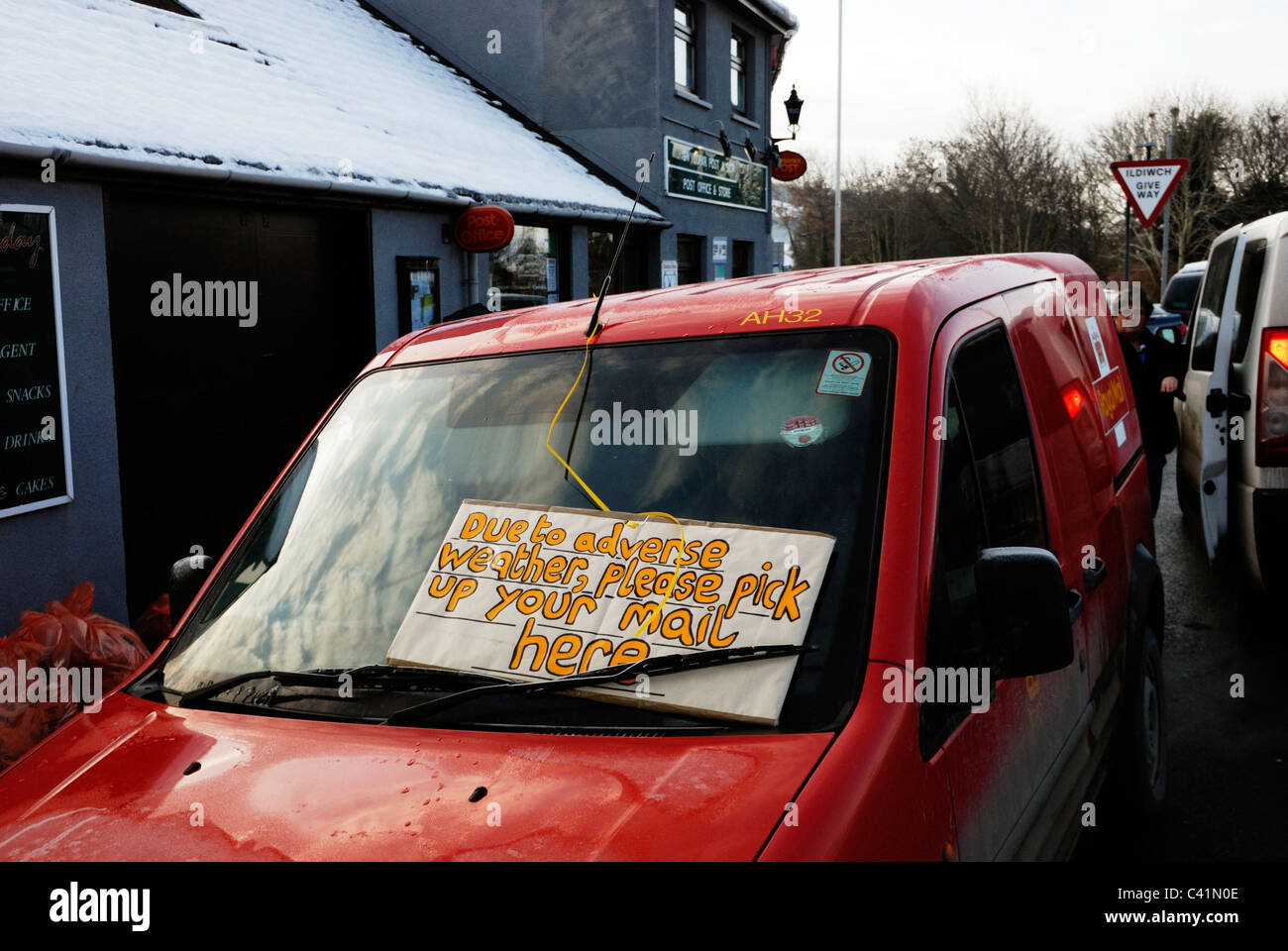 Post van parked in Llanrhystud village with sign reading 'Due to adverse weather please pick up your mail here', Winter 2010/11. Stock Photo