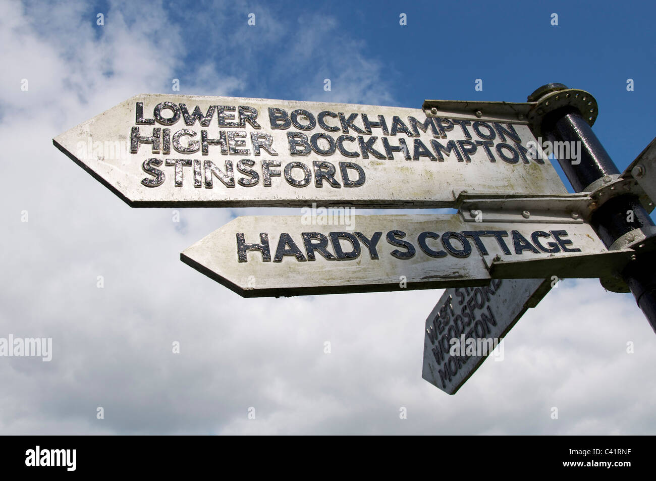 An old wooden signpost points the way to Thomas Hardy’s cottage, at Higher Bockhampton, and to Stinsford church, where he is buried. Dorset, England. Stock Photo