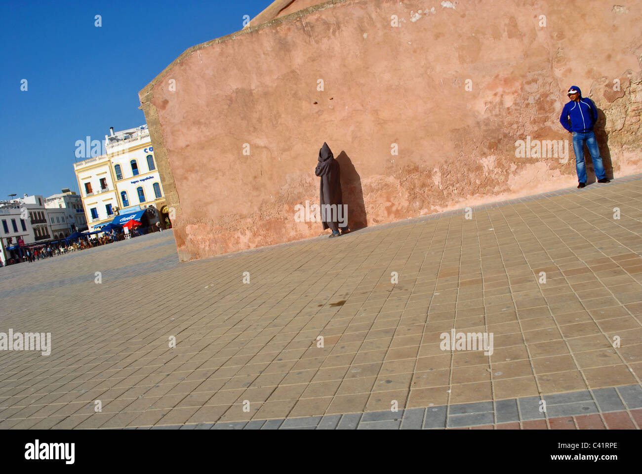 People stand against a wall in the main square in Essaouira, Morocco Stock Photo