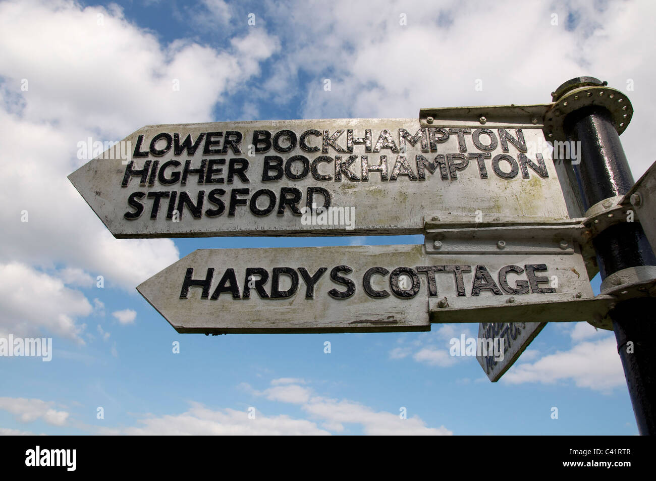 An old wooden signpost points the way to Thomas Hardy’s cottage, at Higher Bockhampton, and to Stinsford church, where he is buried. Dorset, England. Stock Photo