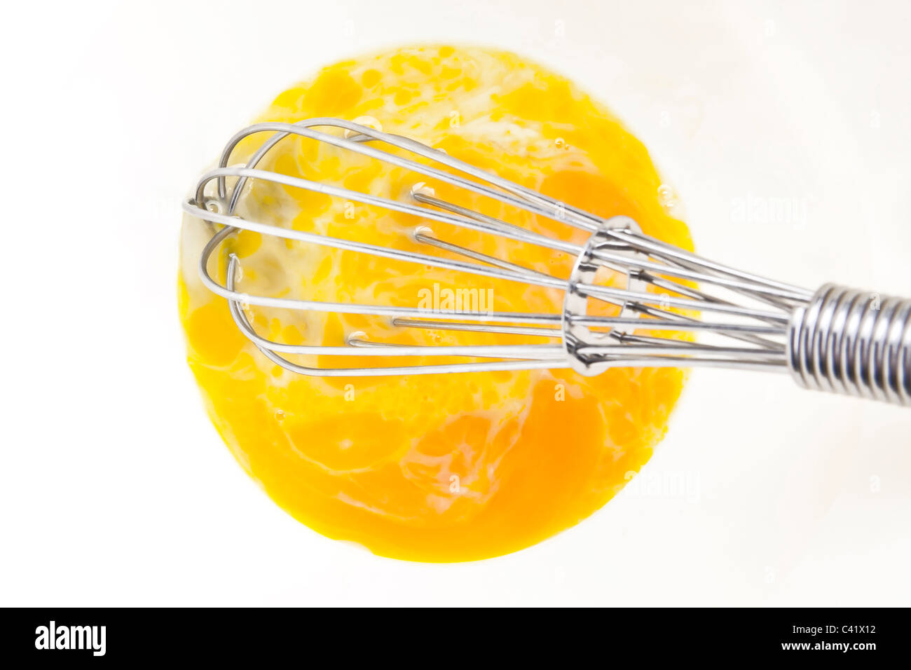 Eggs mixed with milk in a white bowl with whisk Stock Photo