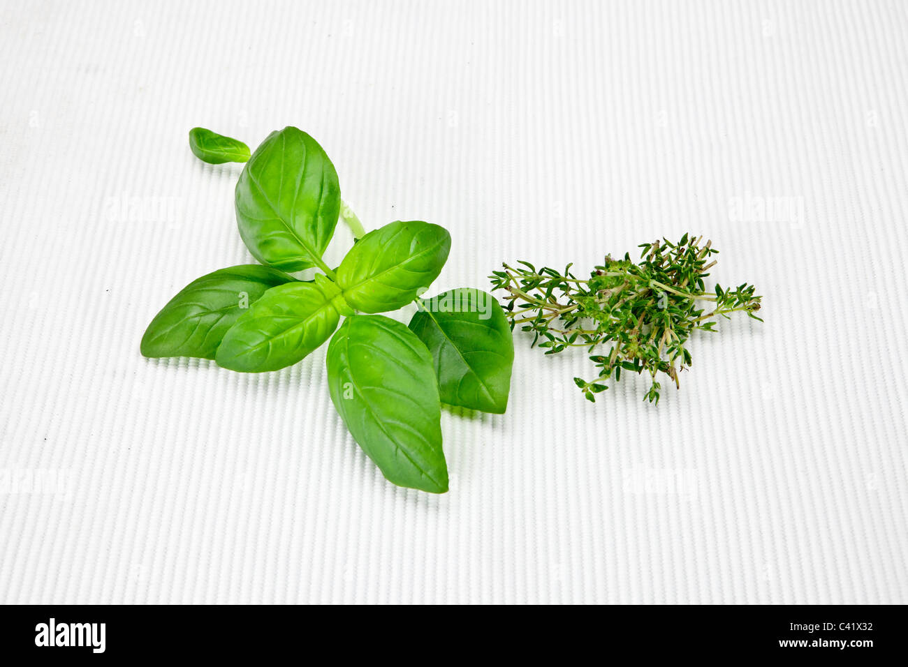 fresh basil leaves and fresh thyme on a white mat Stock Photo