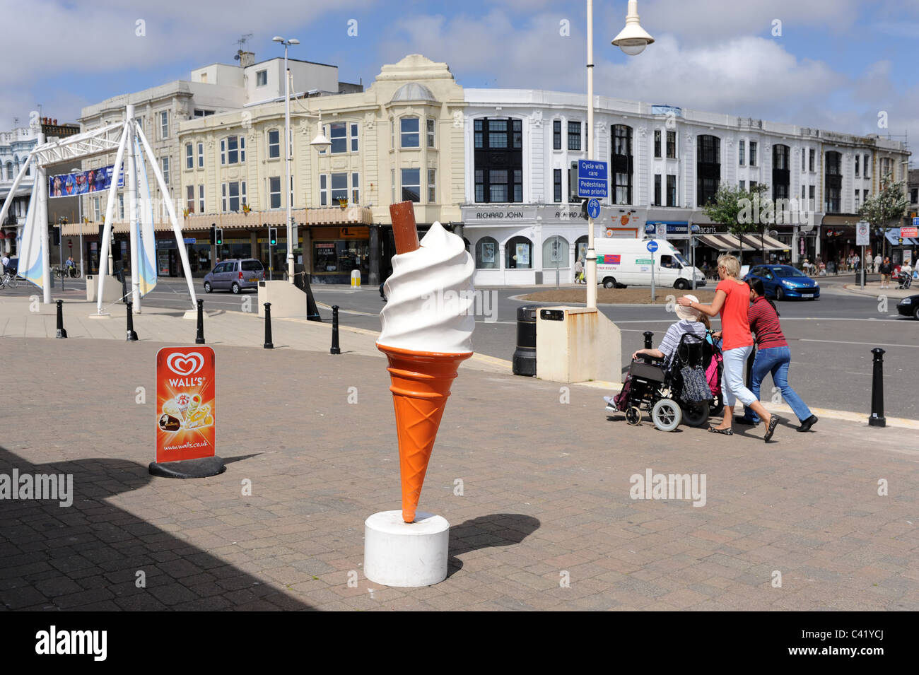 People walking along Worthing seafront passing a giant ice cream cone
