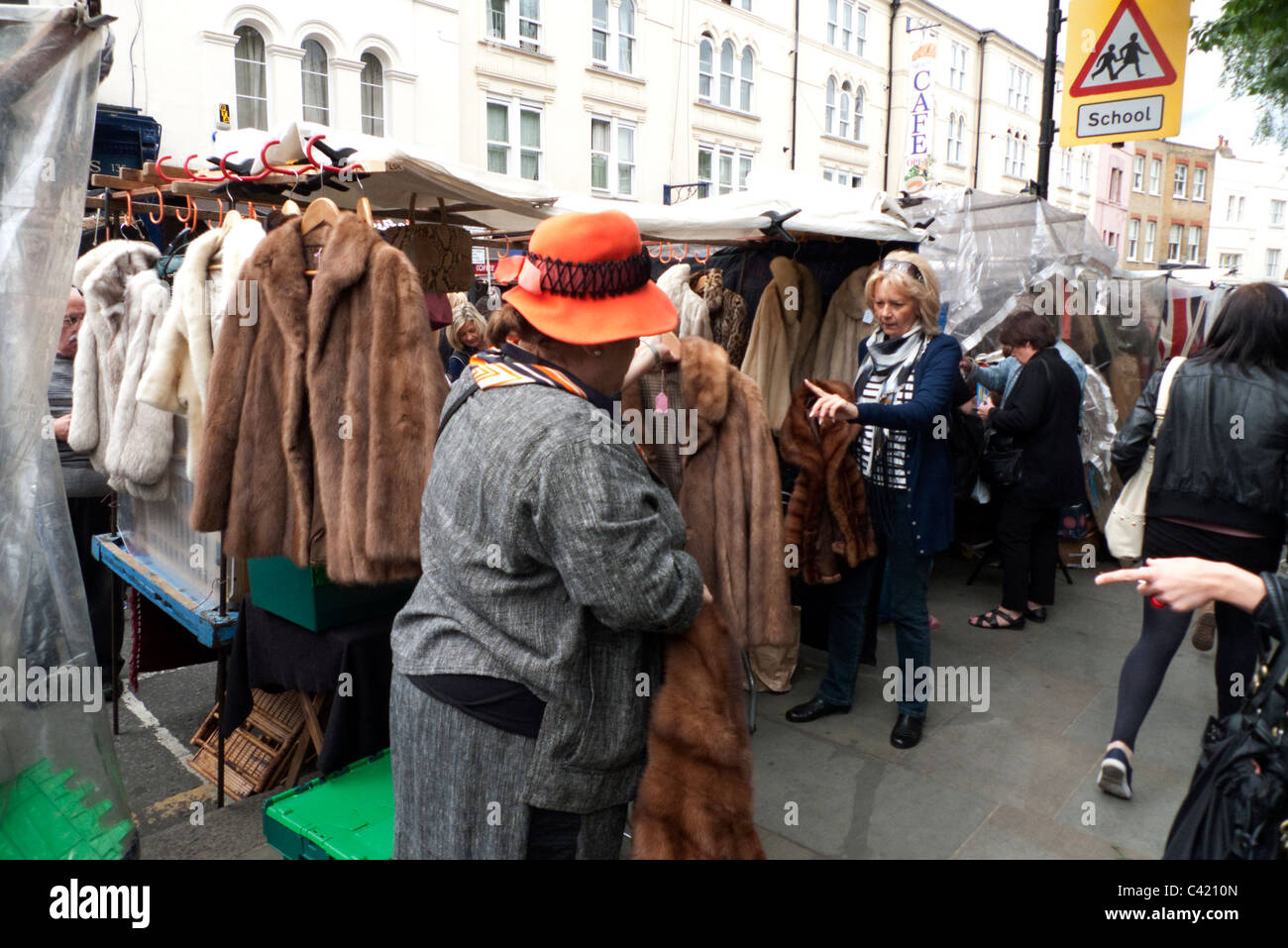 People buying vintage fur coats and jackets on a Portobello Road market stall Notting Hill London England UK Stock Photo