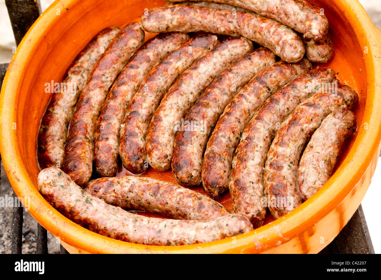 pork sausages in a row clay casserole Spain unhealthy food Stock Photo