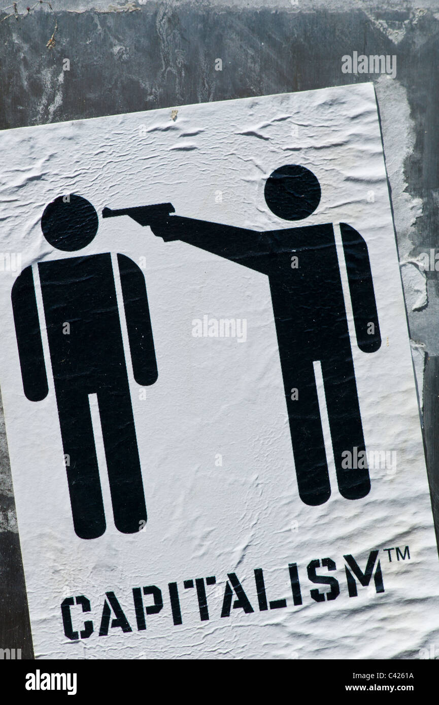 Sticker showing a pictograph with two per sons one pointing a pistol a the others head with the subtitle CAPITALISM TM Stock Photo