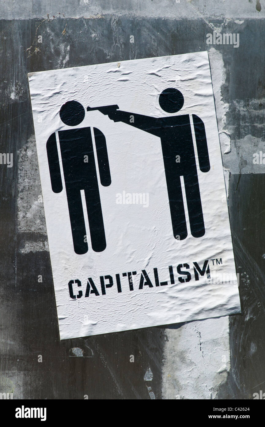 Sticker showing a pictograph with two per sons one pointing a pistol a the others head with the subtitle CAPITALISM TM Stock Photo