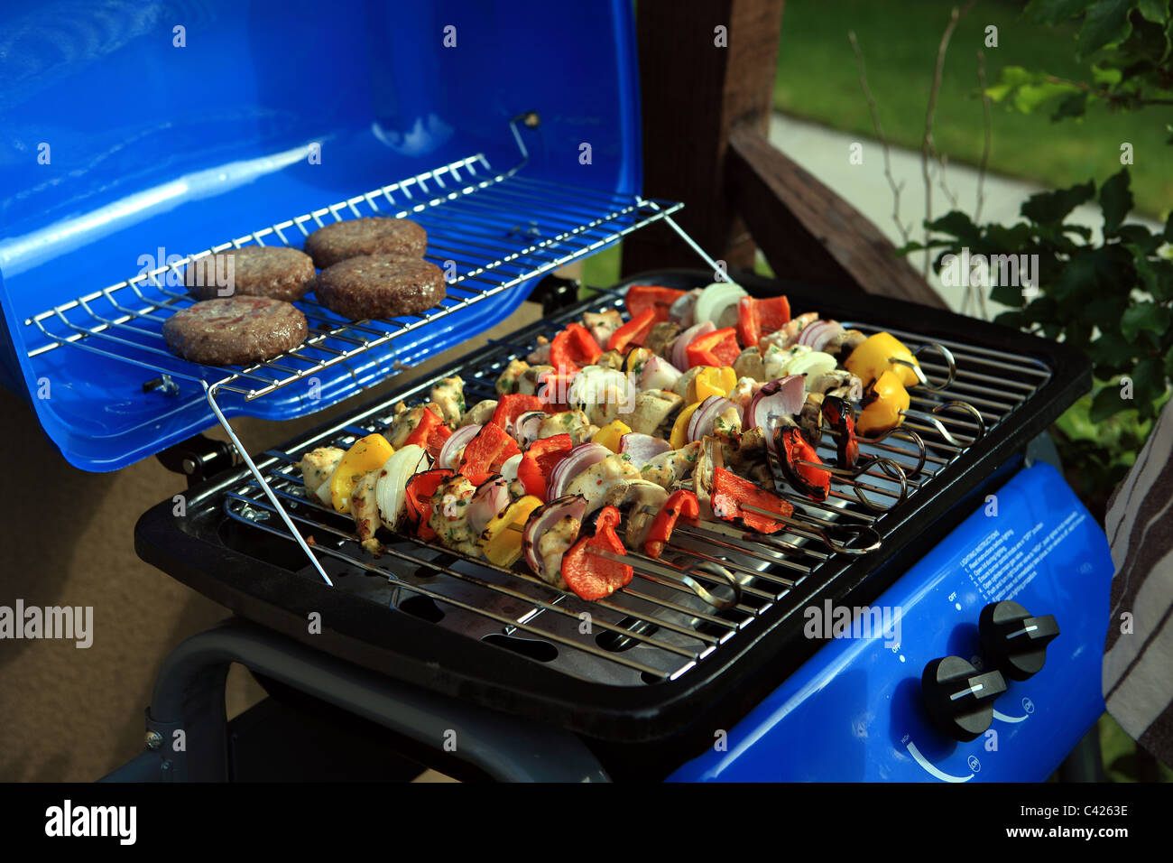 BBQ with vegetables on skewers and burgers Stock Photo