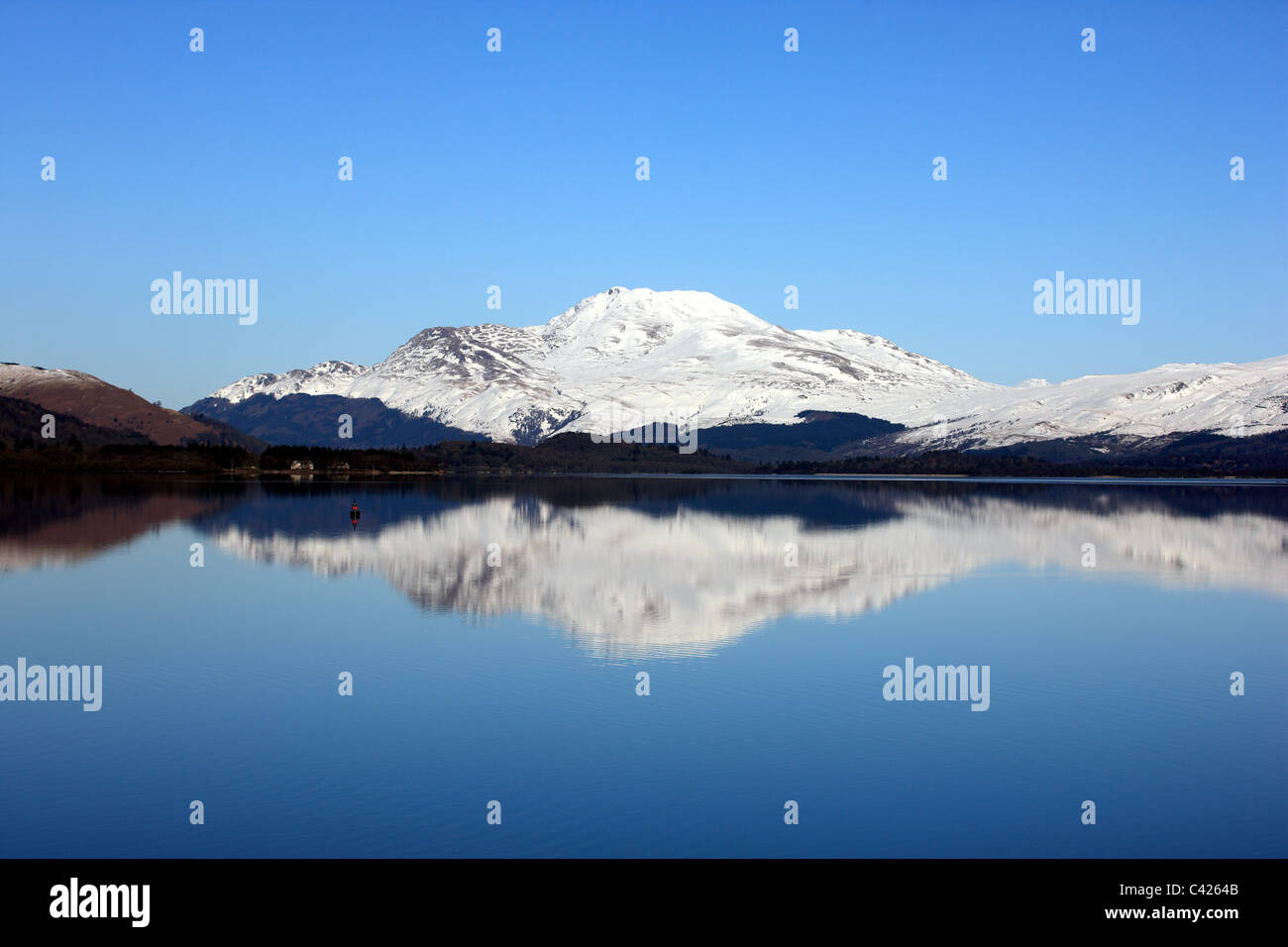 Ben Lomond with winter snow reflected in a very calm Loch Lomond Stock