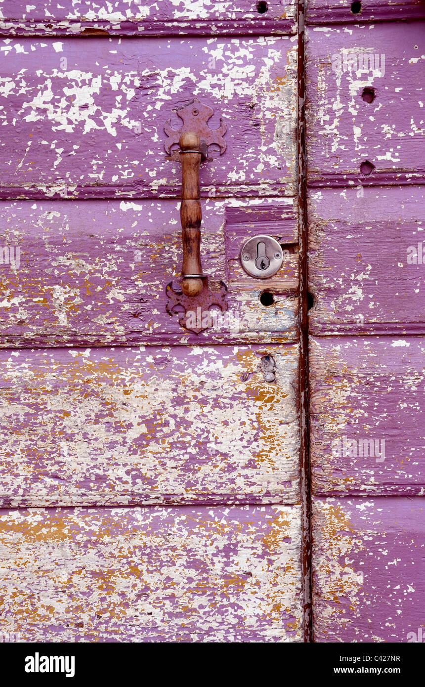 Background of an old painted, crumbled door. Handle on purple wooden planks. Stock Photo