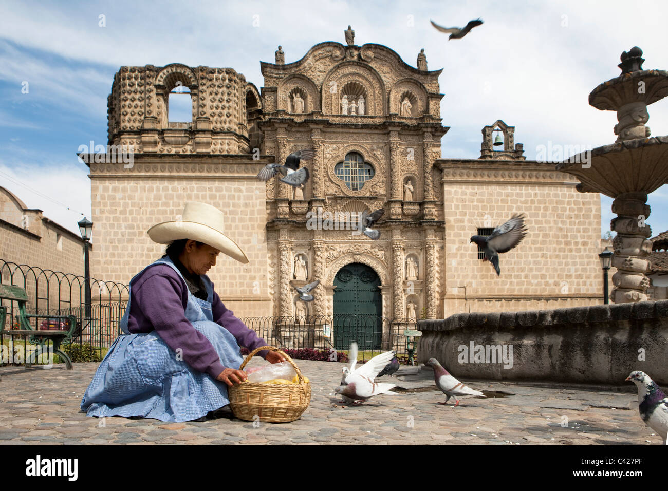 Indian woman with typical hat, selling food for pigeons in front of Belen church, made entirely from vulcanic rock Stock Photo